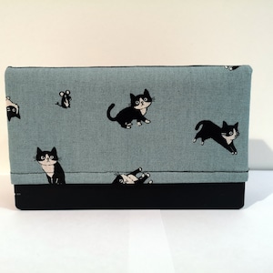May include: A blue fabric clutch with a black and white cat and mouse design. The clutch has a black flap.