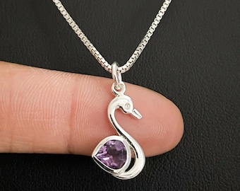 Pode incluir: Um colar de corrente de prata com um pingente em forma de cisne com uma gema de ametista roxa no centro.