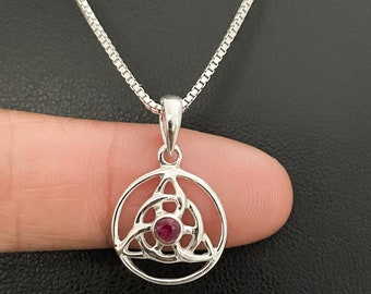May include: Silver necklace with a circular pendant featuring a Celtic knot design with a red gemstone in the center.