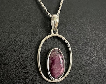 May include: A silver chain necklace with a pendant featuring a purple oval gemstone set in a silver oval frame.