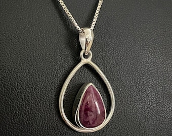 May include: A silver chain necklace with a teardrop-shaped pendant. The pendant features a purple gemstone set in a silver frame.