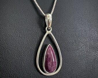 May include: A silver necklace with a teardrop-shaped pendant featuring a purple gemstone.