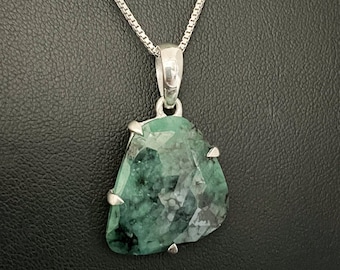 May include: A silver chain necklace with a green gemstone pendant. The pendant is a faceted, irregular shape with a silver setting.