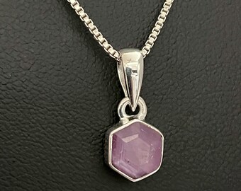 May include: A silver chain necklace with a pendant featuring a faceted purple gemstone set in a silver bezel.