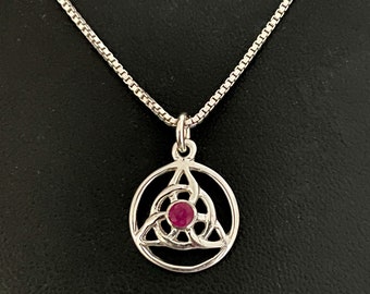 May include: A silver necklace with a pendant featuring a Celtic knot design with a ruby gemstone in the center.