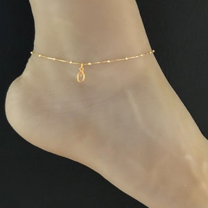 Puede incluir: Un delicado tobillo de oro con un pequeño dije redondo. El tobillo está hecho de una cadena fina con pequeñas cuentas.