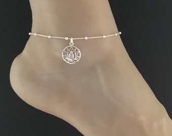 Könnte beinhalten: Silbernes Fußkettchen mit einer zarten Kette und einem Lotusblüten-Anhänger. Der Anhänger hat einen klaren Stein in der Mitte.