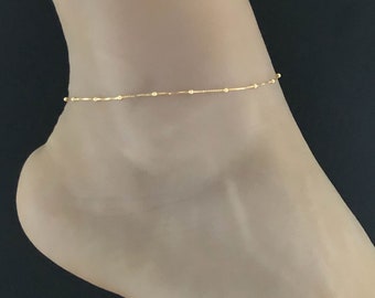May include: A delicate gold anklet with a chain and small beads.