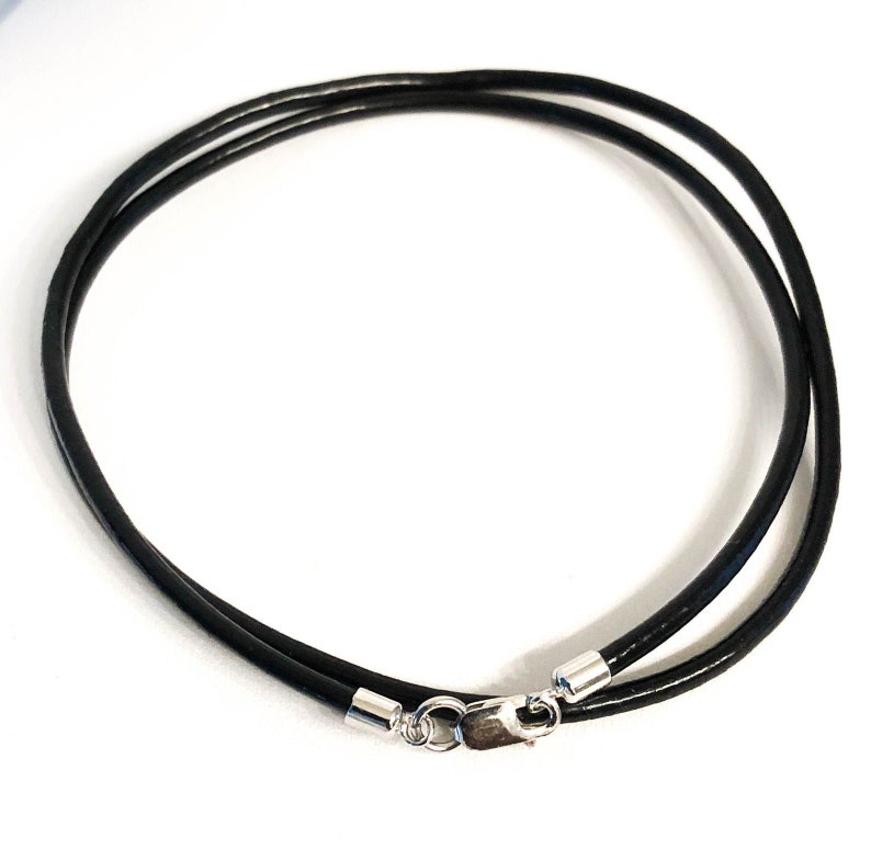 May include: A black leather cord necklace with silver clasps.