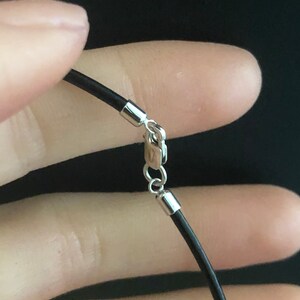 May include: A black leather cord necklace with a silver clasp.