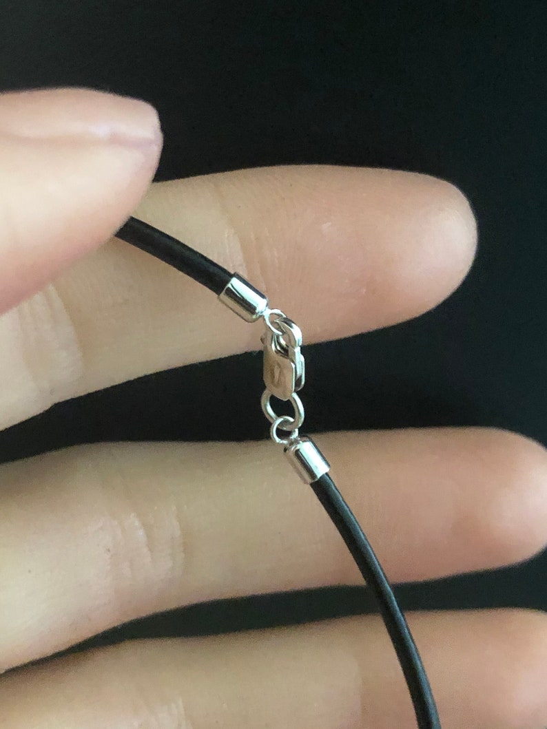 May include: A black leather cord necklace with a silver clasp.