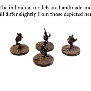 May include: Four miniature black and red figures on round brown bases. The figures are in various poses and appear to be made of metal.