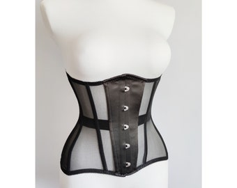 Può includere: Un corsetto nero in mesh e raso con ganci e occhielli in metallo argentato. Il corsetto ha una struttura a stecche e un pannello in raso liscio sul davanti.