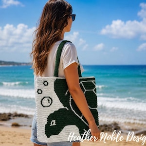 May include: A square crochet tote bag featuring a dark green sea turtle design on a white background with small circular bubble motifs. The bag has two matching dark green shoulder straps and is constructed with a textured yarn stitch pattern.
