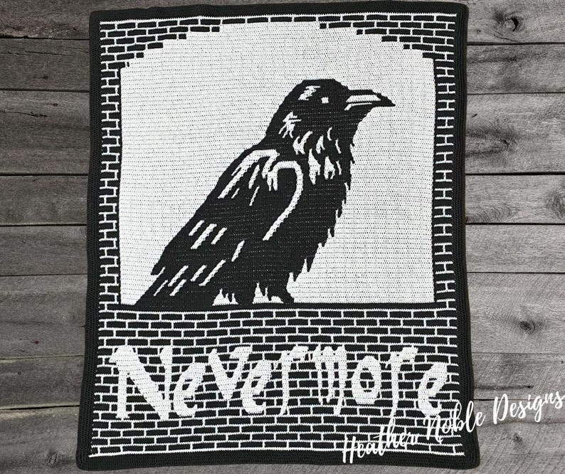 May include: Black and white crocheted blanket featuring a raven design. The raven is perched within a white rectangle, with the word "Nevermore" in white block letters below. The blanket has a brick-like border.