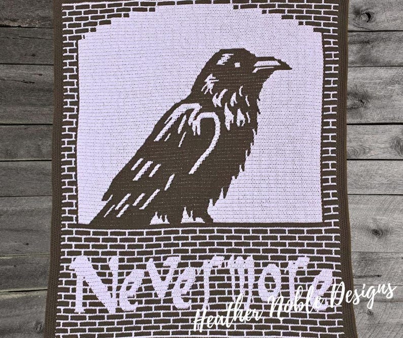 May include: A crocheted blanket featuring a raven design in shades of brown and white. The raven is set against a white background, framed by a brick-like border. The words "Nevermore" are displayed at the bottom.