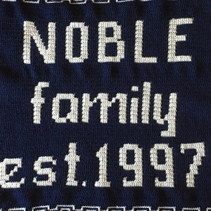 May include: A navy blue crocheted blanket with white lettering that reads "NOBLE family est. 1997".