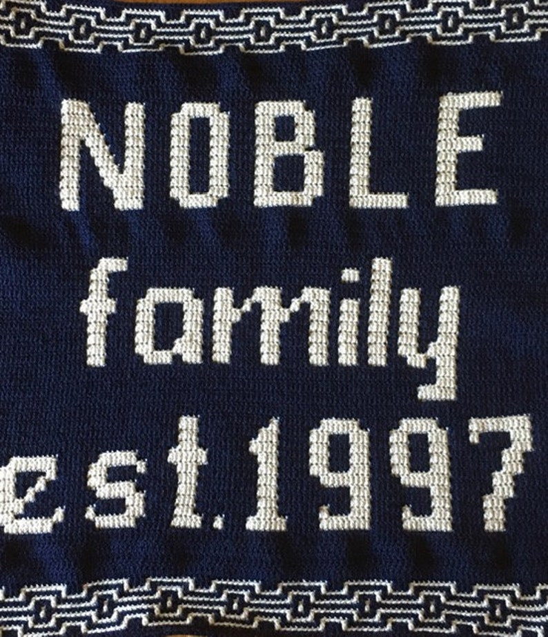 May include: A navy blue crocheted blanket with white lettering that reads "NOBLE family est. 1997".