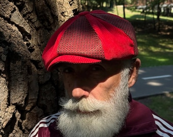 May include: A newsboy cap featuring alternating panels of vibrant red corduroy and a dark brown textured fabric. The cap has a structured brim and a multi-paneled crown design, showcasing a distinct contrast between the bright red and dark brown materials.