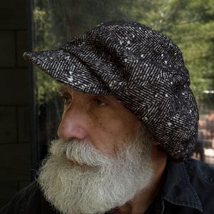 Peut inclure: Une casquette gavroche à motif chevrons noir et blanc avec une finition texturée et une visière courte et rigide. La casquette présente une construction classique à plusieurs panneaux avec une calotte arrondie, en tissu tissé avec des mouchetures.