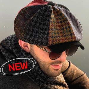 Puede incluir: Una gorra de estilo newsboy de varios paneles con un diseño de patchwork de patrones de pata de gallo y cuadros en tonos rojo, negro, marrón y azul, con una visera negra sólida y un pequeño botón negro en la parte superior. La palabra NEW está en rojo.