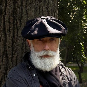 May include: A black newsboy cap with a rounded, paneled crown and a short, stiff brim. The cap features a button detail at the center top and is constructed from a dark, textured fabric, providing a classic silhouette that sits low on the head.