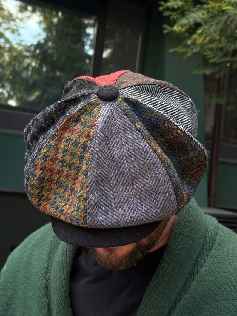 May include: A patchwork newsboy cap with a black brim and a button on top. The cap features various patterned fabrics in shades of blue, brown, red, and gray. The cap is a stylish accessory.