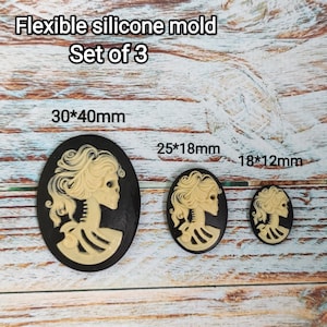 May include: Set of three flexible silicone molds for making cameo-style resin crafts. The molds are black and feature a skeleton woman design. The molds are 30mm x 40mm, 25mm x 18mm, and 18mm x 12mm.