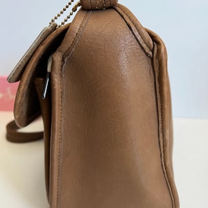 May include: A brown leather shoulder bag with a flap closure and a gold chain strap.