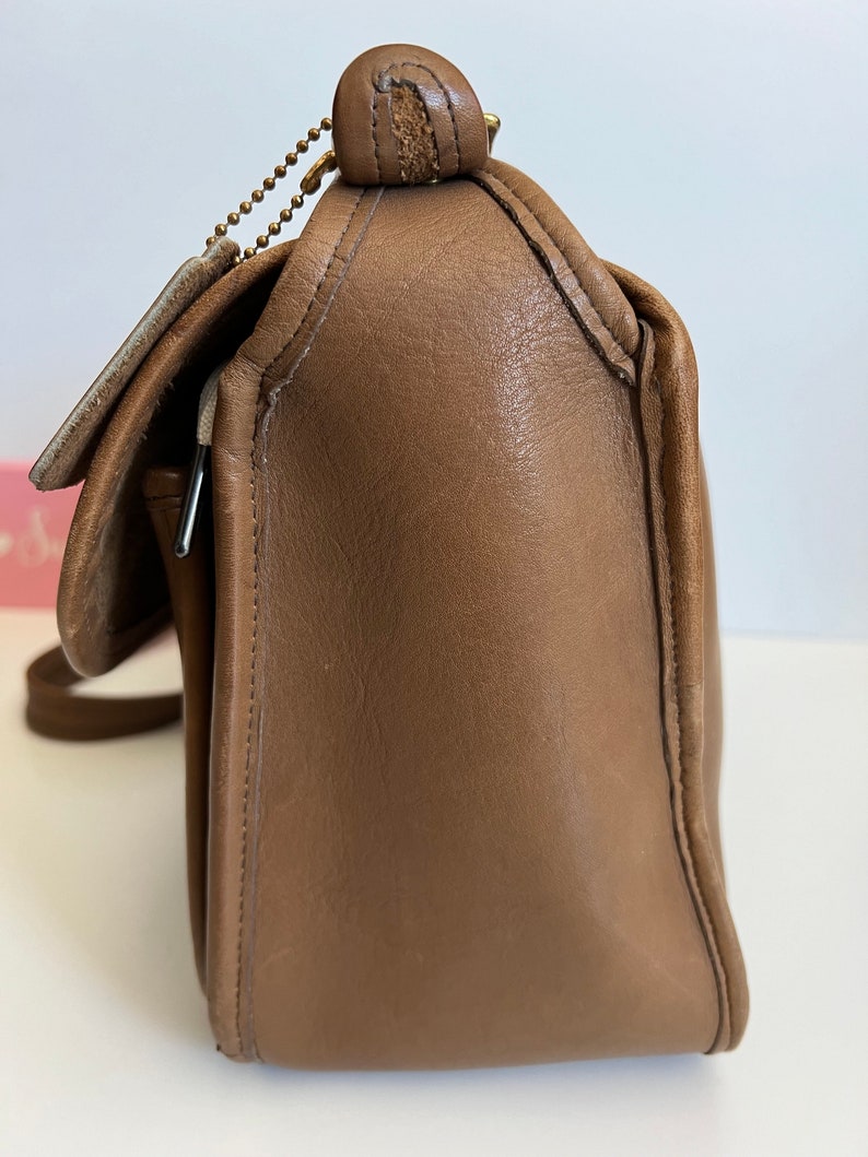 May include: A brown leather shoulder bag with a flap closure and a gold chain strap.
