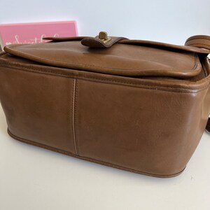 May include: A brown leather shoulder bag with a brass clasp. The bag has a rectangular shape and a flap closure.