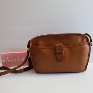 May include: A brown leather shoulder bag with a flap closure and a gold-toned buckle. The bag has a single strap and a small pocket on the front.