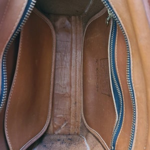 May include: The inside of a brown leather bag with a zipper closure. The bag has a label that reads "No. 144-9344".