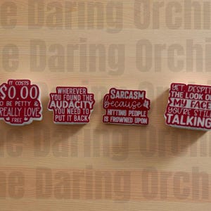 May include: Four red and white rectangular stickers with humorous phrases. The stickers read: "It costs $0.00 to be petty & I really love free", "Wherever you found the audacity you need to put it back", "Sarcasm because hitting people is frowned upon", and "Yet, despite the look on my face you're still talking."