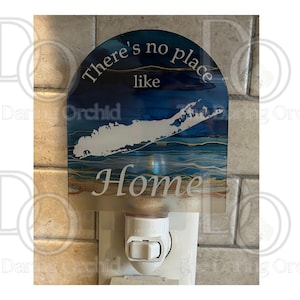 May include: A decorative night light with a blue and gold design featuring the text "There's no place like Home" and a white outline of Long Island. The night light plugs into a standard wall outlet.
