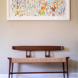 May include: A wooden bench with a woven seat and a simple, mid-century modern design. The bench has a dark brown finish and is sitting on a hardwood floor.