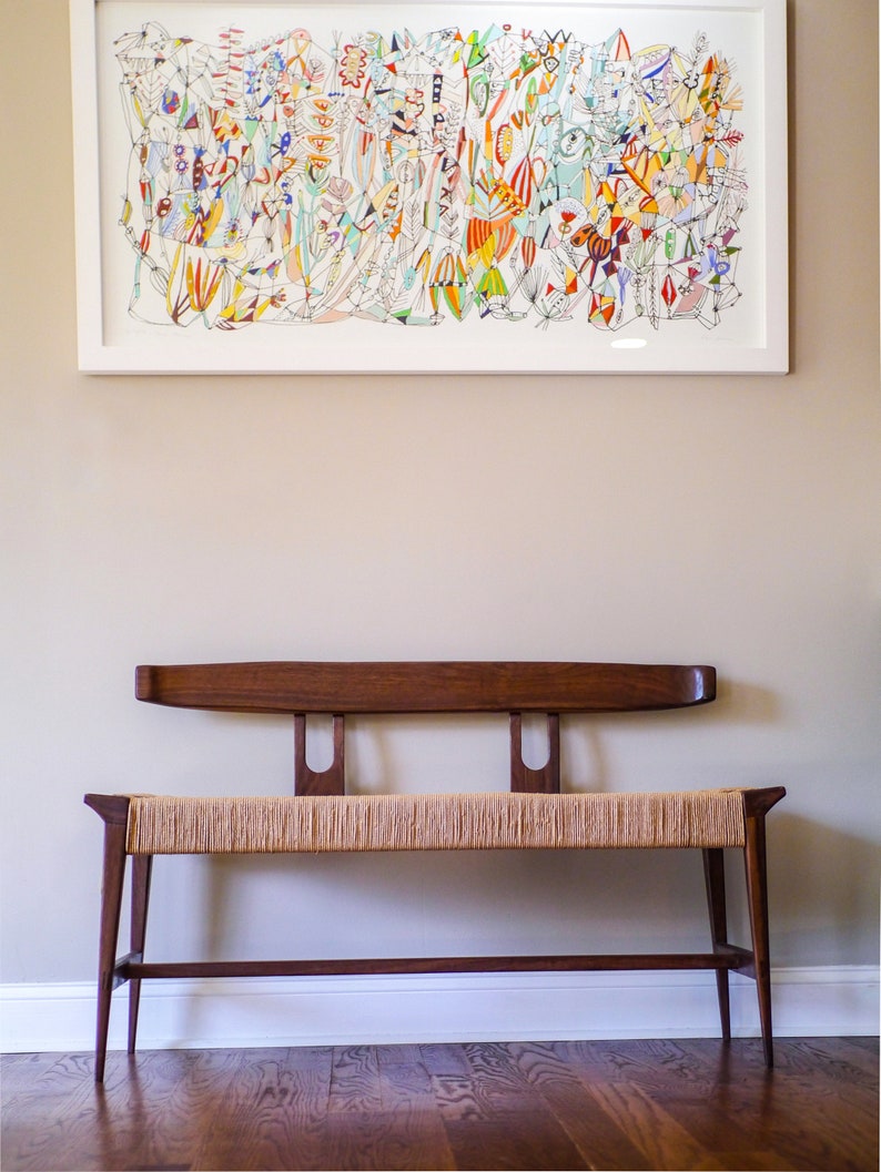 May include: A wooden bench with a woven seat and a simple, mid-century modern design. The bench has a dark brown finish and is sitting on a hardwood floor.