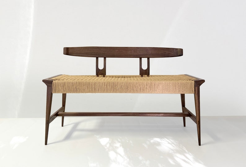 May include: A dark wood bench with a woven cane seat and a back rest. The bench has a simple, modern design.