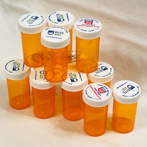 May include: Ten clear orange plastic pill bottles with white lids. The lids have a blue and red logo that says "Rite Aid" and the website address "www.riteaid.com".