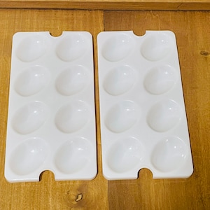 May include: Two white plastic egg cartons with six compartments each. The cartons are empty and have a smooth, glossy finish.