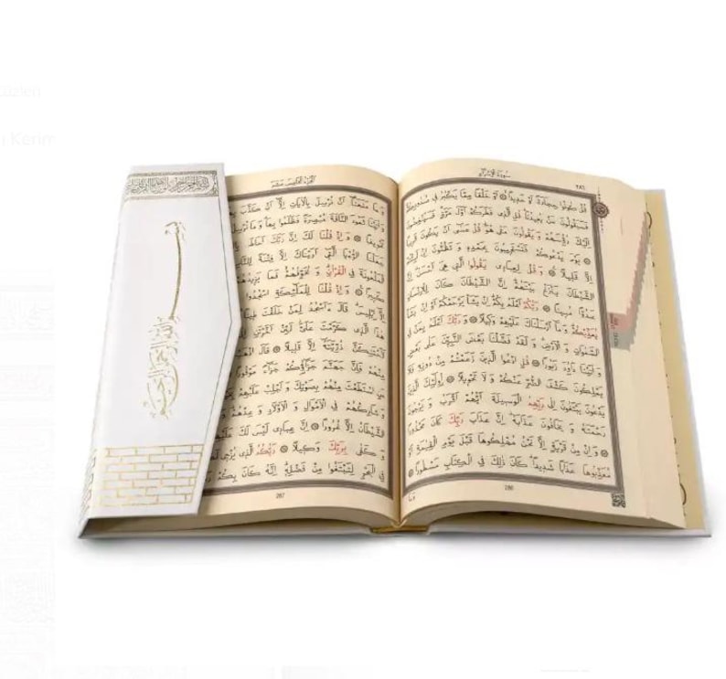 May include: An open book with white pages and gold accents. The book is open to a page with Arabic text. The book is on a white background.