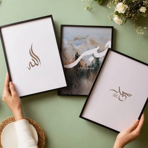 Könnte beinhalten: Drei rechteckige Wandbilder in dünnen schwarzen Rahmen. Ein Druck zeigt braune arabische Kalligrafie auf weißem Grund. Ein weiterer zeigt eine Landschaft mit weißem arabischem Text und dem Schriftzug is key to jannah. Der dritte zeigt braune Kalligrafie.