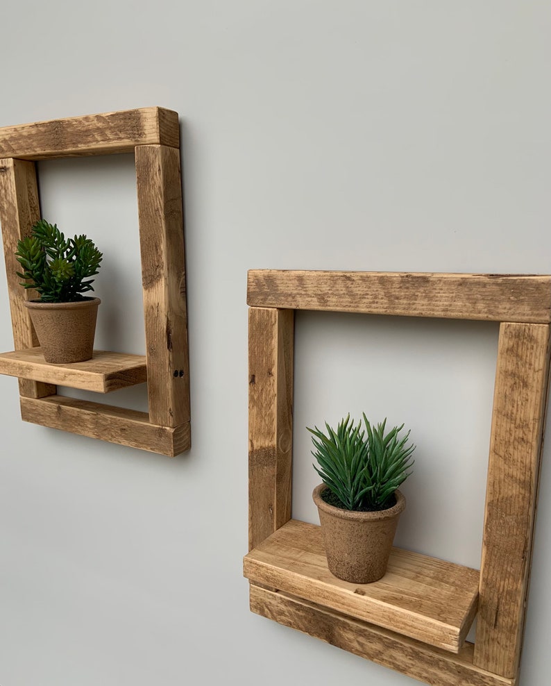 May include: Two rustic wooden shelves with a square frame and a small shelf. Each shelf has a potted succulent plant on it.