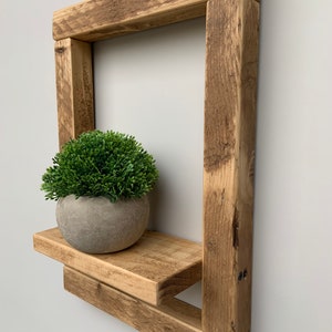 May include: Rustic wooden shelf with a single shelf and a small potted plant. The shelf is made of reclaimed wood and has a natural, weathered finish.