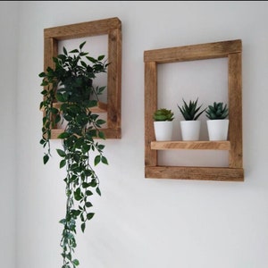 May include: Two rustic wooden wall shelves with a natural wood finish. The top shelf is empty, while the bottom shelf holds three small potted succulents. The shelf on the left has a hanging plant with green leaves.