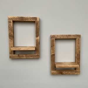 May include: Two rustic wooden shelves with a simple design. The shelves are made of reclaimed wood and have a natural finish. They are perfect for adding a touch of farmhouse style to any room.