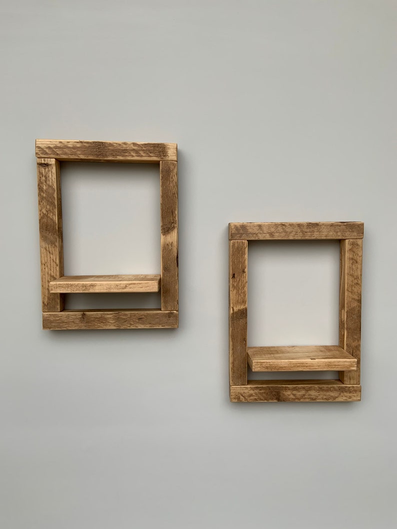 May include: Two rustic wooden shelves with a simple design. The shelves are made of reclaimed wood and have a natural finish. They are perfect for adding a touch of farmhouse style to any room.