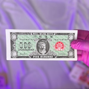 Pode incluir: Uma nota de banco do inferno verde e preta com o texto "HELL BANK NOTE" e "FIVE HUNDRED" impresso nela. A nota apresenta um retrato de um homem com uma longa barba e uma coroa. A nota também tem o número "500" impresso nela.