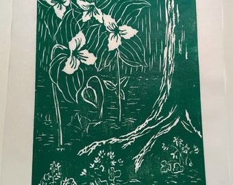 May include: A green linocut print of white flowers with leaves and a tree trunk. The flowers are in the center of the print and the tree trunk is on the right side of the print.