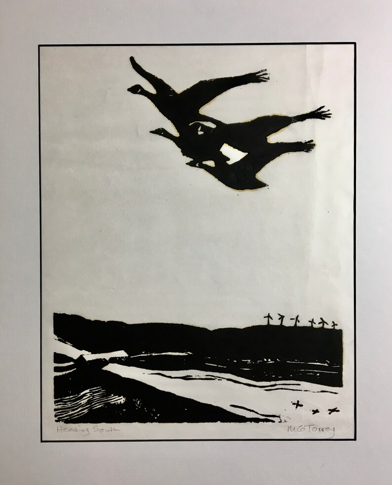 May include: Black and white linocut print of a flock of geese flying over a landscape with trees and the text "Heading South" and the artist's signature "M.G.Torrey".